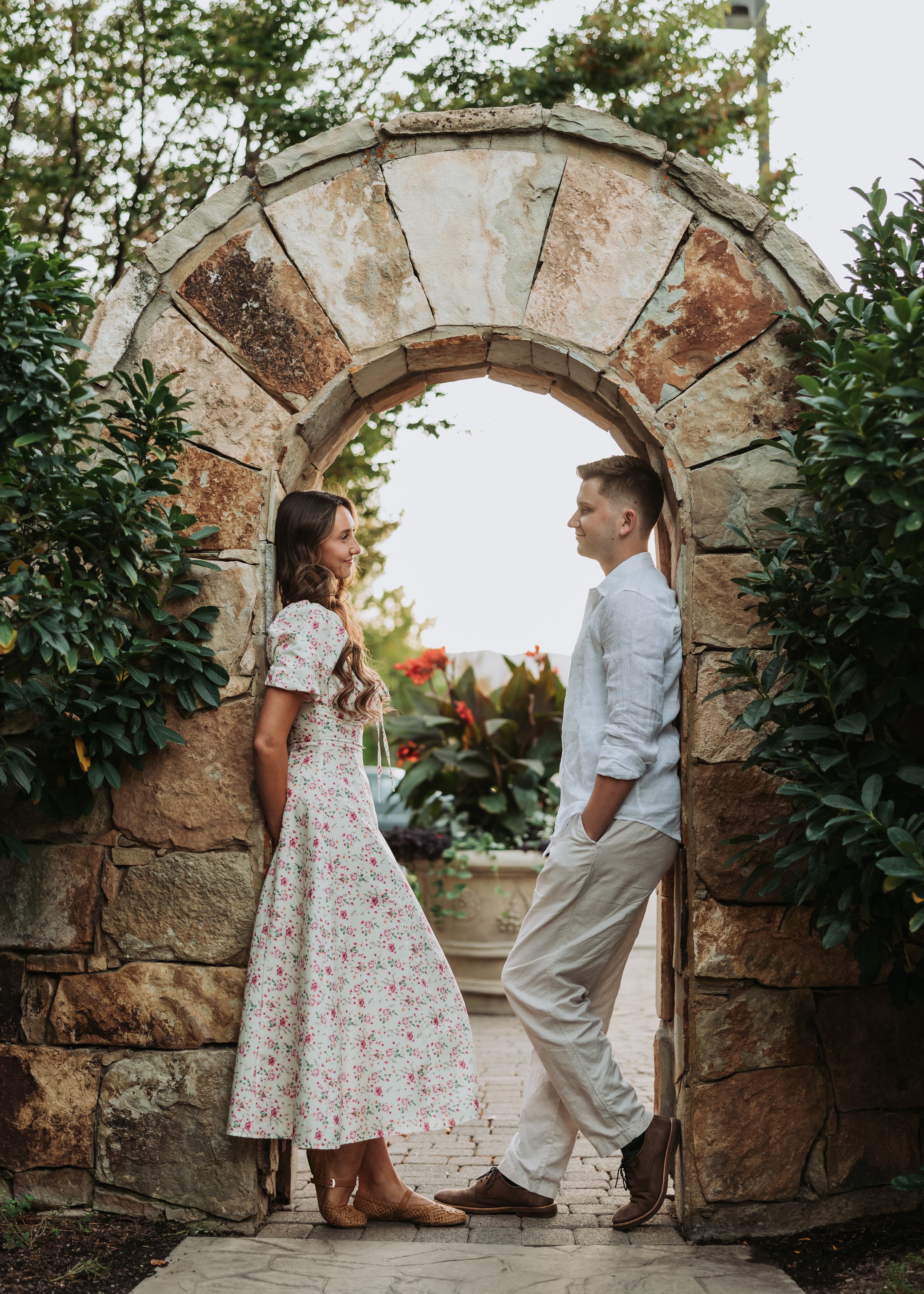 Bre and Bronson facing each other beneath a stone garden arch